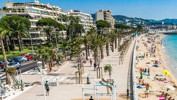 Une plage équipée d’installations de remise en forme, une promenade et des bâtiments en arrière-plan.