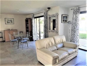 Un salon avec un canapé beige, une table à manger avec des chaises et un buffet.