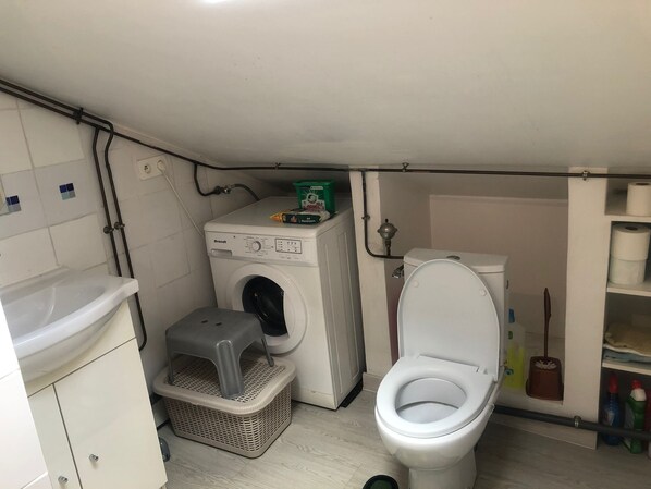 A compact laundry room with a washing machine, a dryer, a toilet, and a small storage area. - Functional apartment just outside Paris (Villetaneuse)