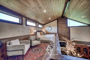 Une pièce confortable avec un lit, une horloge, un ventilateur et un plafond en bois.