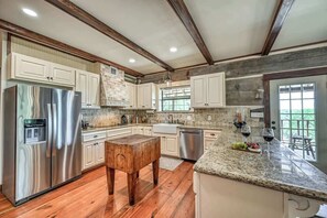 A modern kitchen with wooden beams, stainless steel appliances, and a granite countertop.