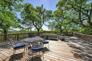 Une terrasse extérieure avec une table ronde et des chaises, entourée d’arbres.