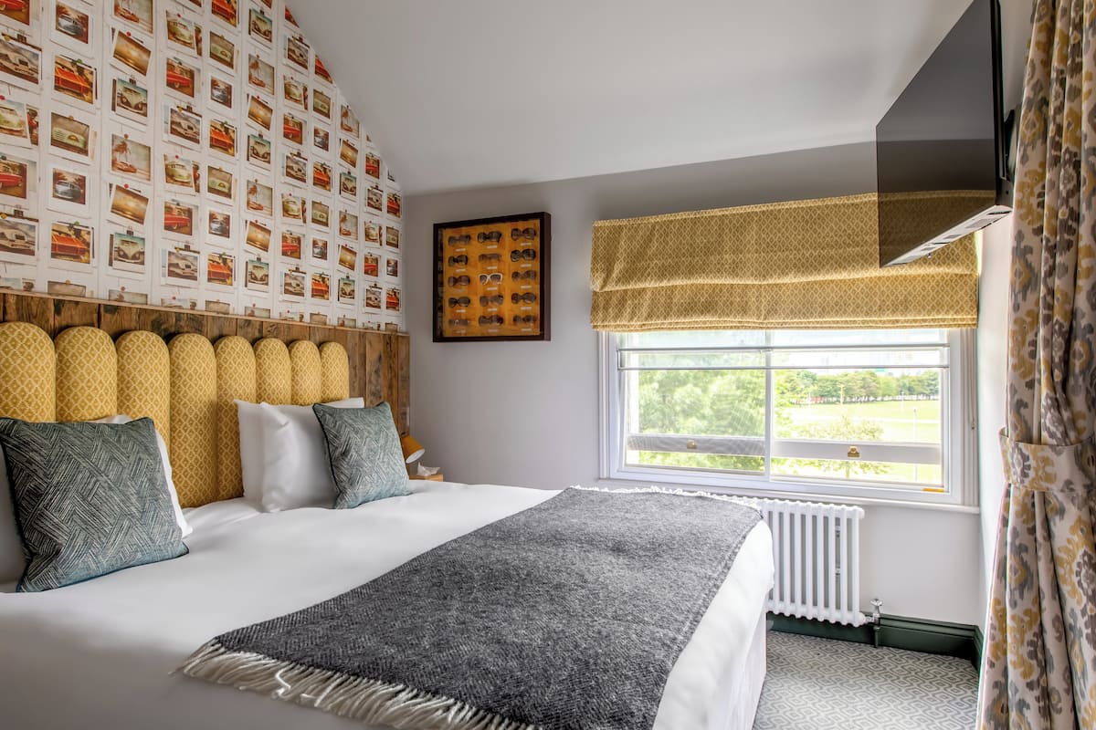Ein ordentlich eingerichtetes Schlafzimmer mit einem großen Bett, einer Wand mit Muster, einem Fenster mit Ausblick und einer Heizung.