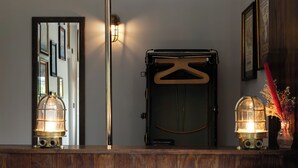 A wooden counter with two vintage-style wall sconces, a mirror, and a door with a hanger. - The Pilot (London)