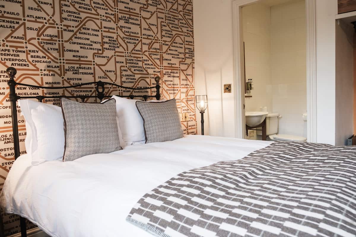 Ein Hotelzimmer mit einem großen Bett, einer Wand voller Karten und einem durch eine geöffnete Tür sichtbaren Badezimmer.