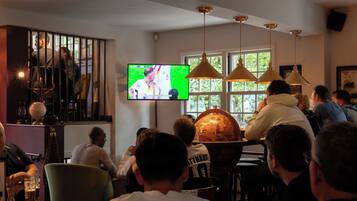 Un bar où des clients regardent un écran de télévision, avec un globe terrestre et des lampes suspendues.
