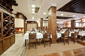 A restaurant with multiple tables, wooden pillars, and a fireplace. - Apartment Tourist Complex & SPA Astera Bansko (Bansko)