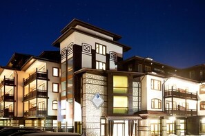 A multi-story hotel with balconies, a stone facade, and illuminated windows at night. - Apartment Tourist Complex & SPA Astera Bansko (Bansko)