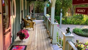A wooden porch with wicker chairs, a welcome mat, and a 'Thank You' sign. - WeatherPine Inn (Niagara-on-the-Lake)