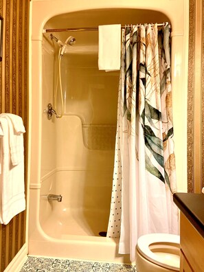 A bathroom with a bathtub, shower, toilet, and a towel rack. - WeatherPine Inn (Niagara-on-the-Lake)