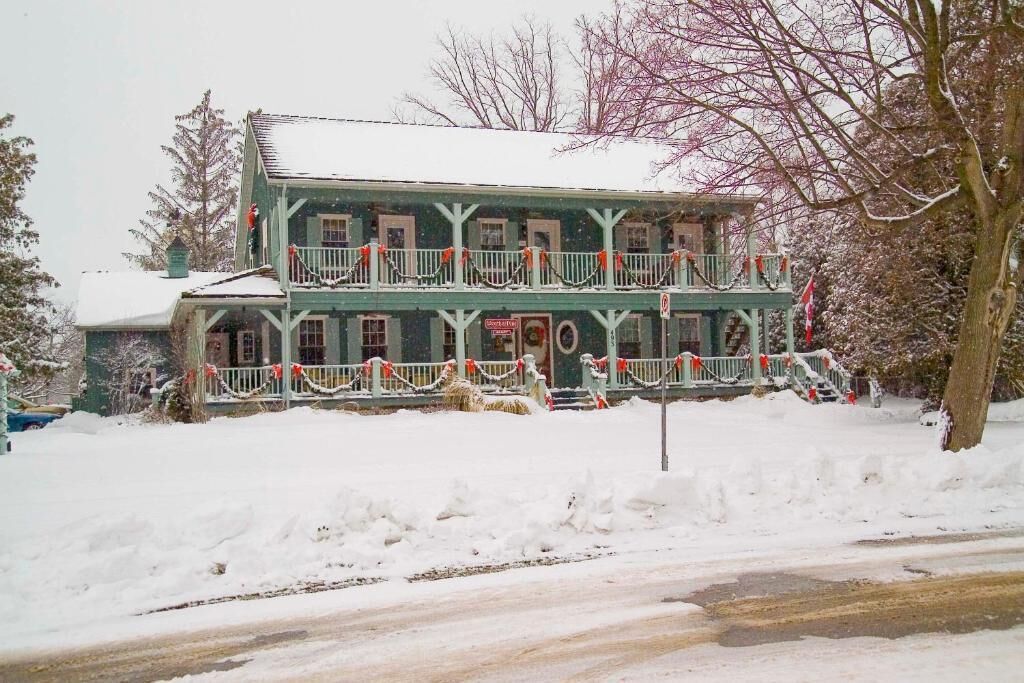 A two-story building with a balcony, surrounded by snow.
