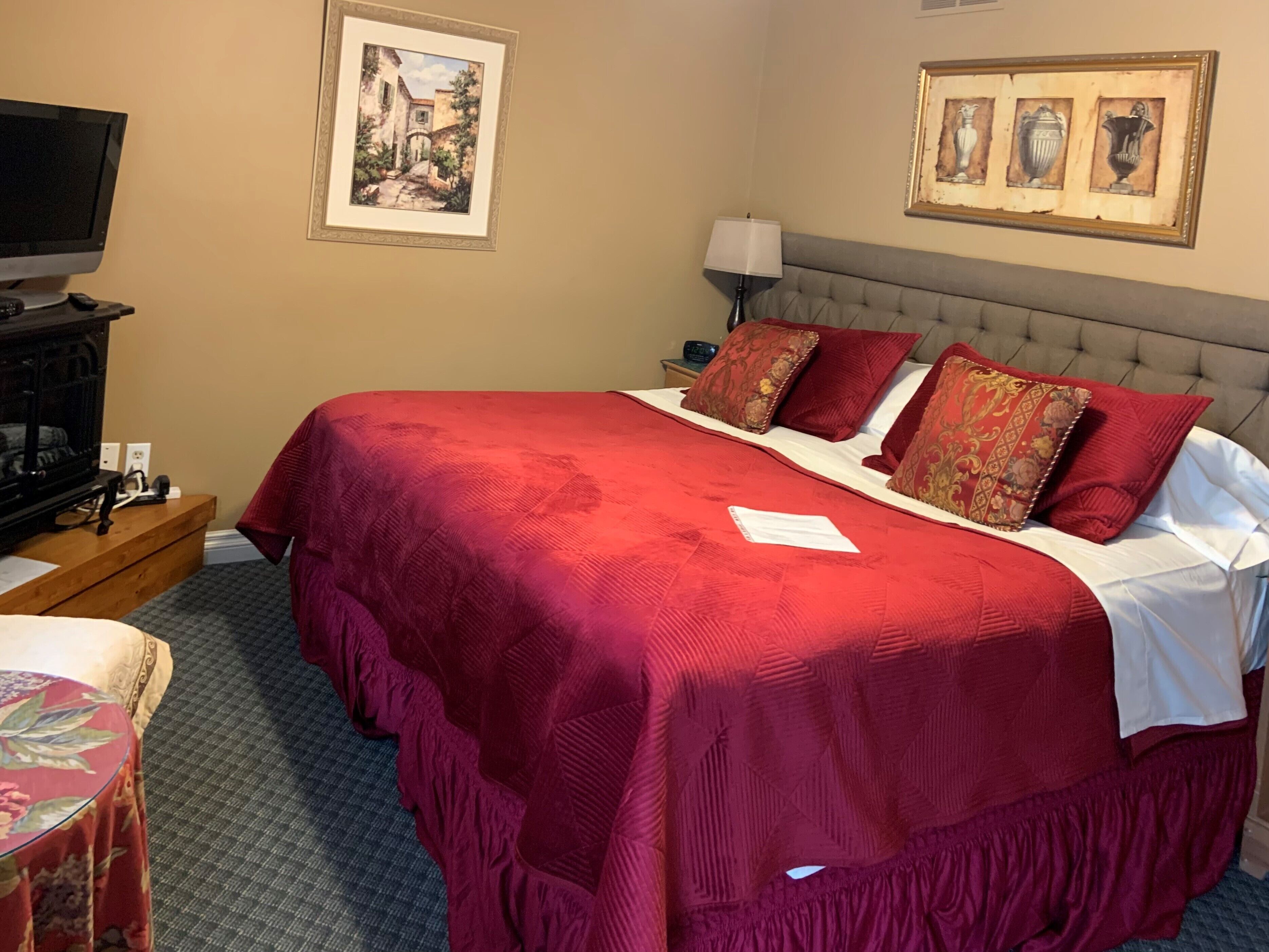 Une chambre d’hôtel avec un grand lit, une télévision, un bureau avec une lampe et des œuvres d’art accrochées aux murs.