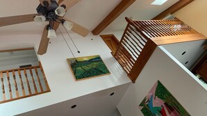 A multi-level interior with wooden beams, a ceiling fan, and artwork on the walls. - WeatherPine Inn (Niagara-on-the-Lake)