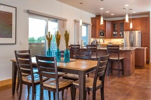 A modern kitchen with wooden cabinets, a central island, and pendant lighting.