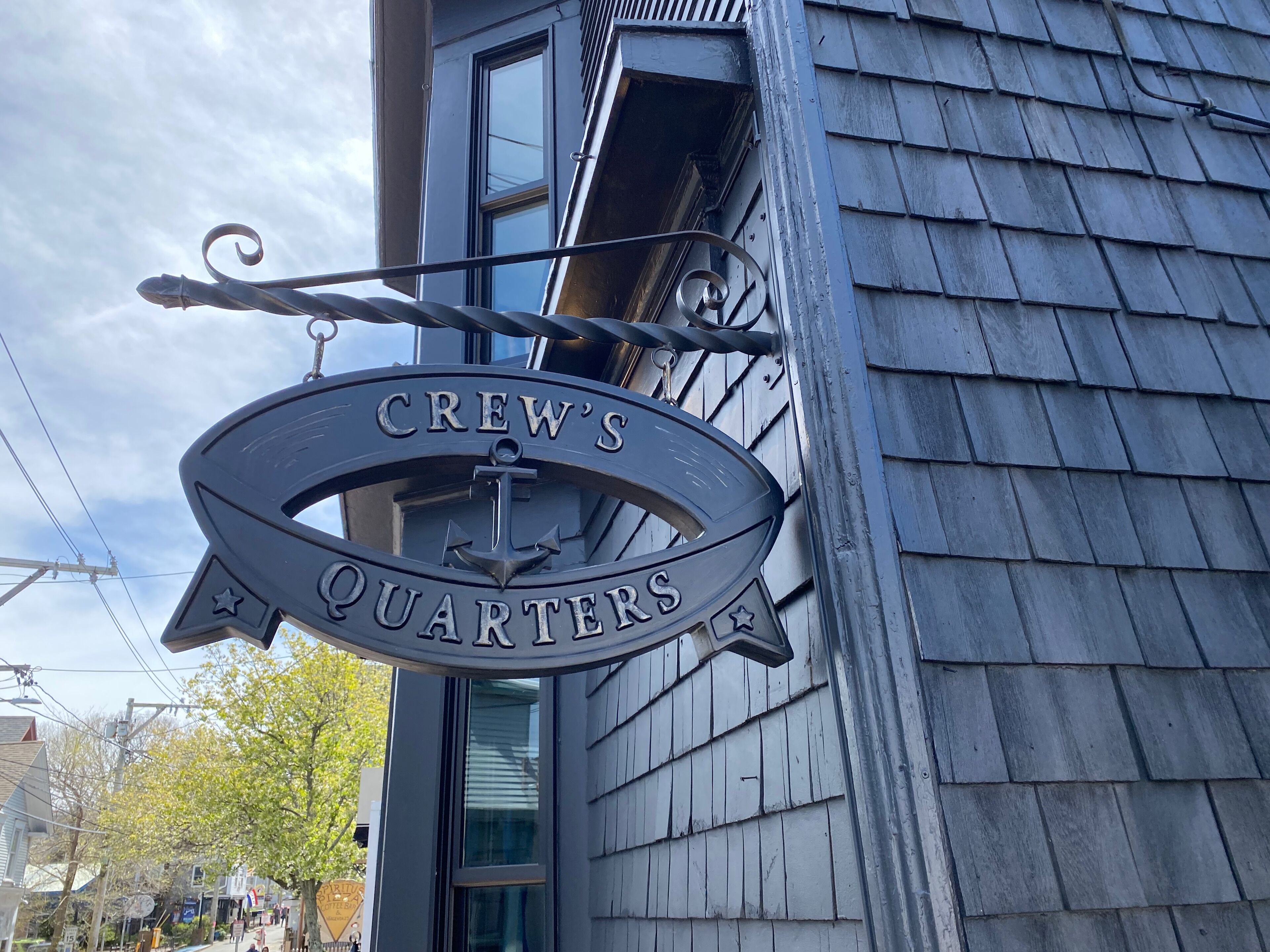 A metal sign with the text "CREW'S QUARTERS" mounted on a building.