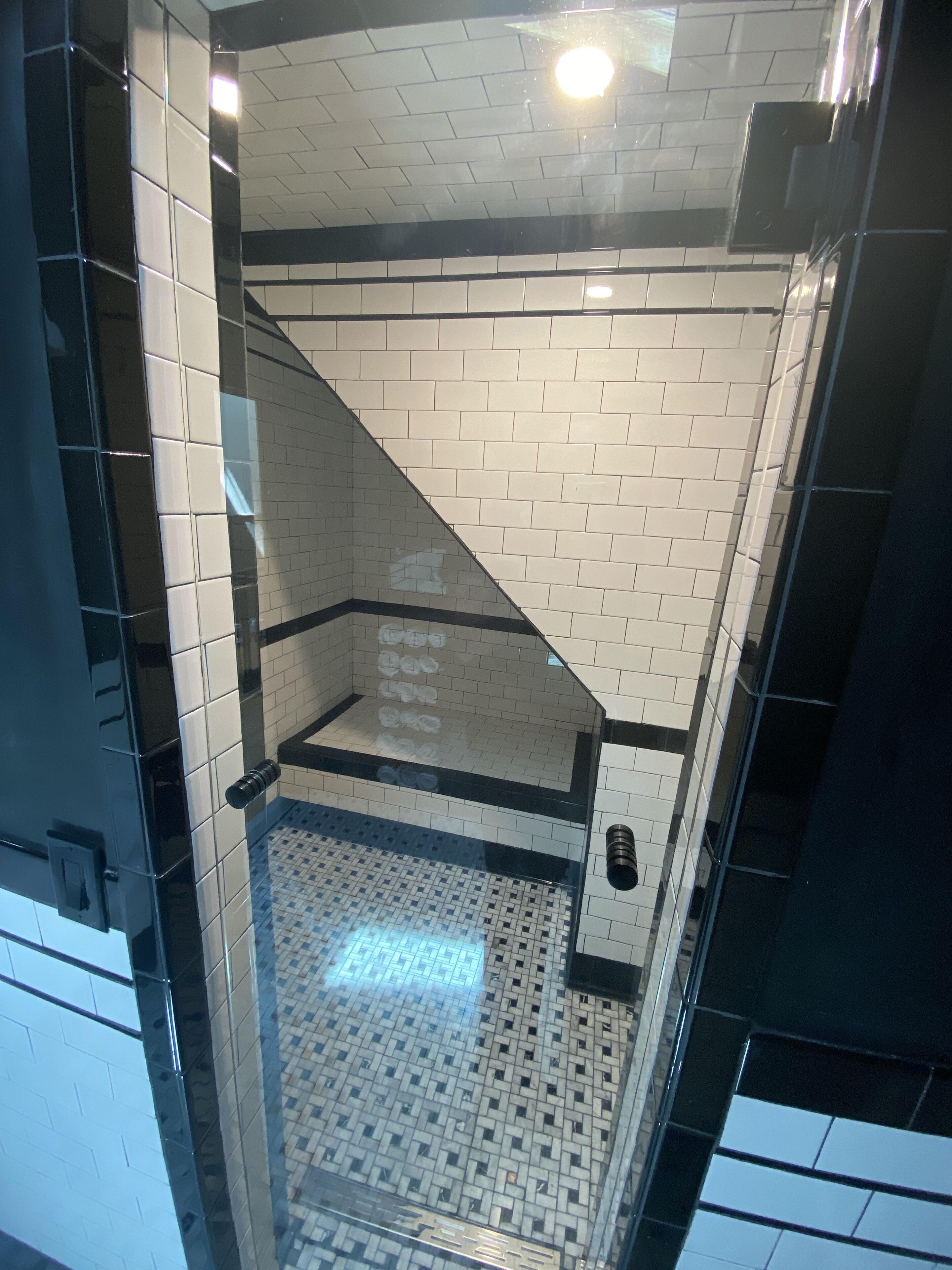 A tiled bathroom with a glass shower enclosure and a patterned floor.