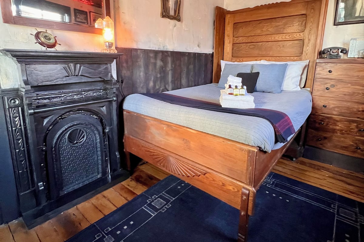 A bedroom with a wooden bed, a wooden dresser, a mirror, and a decorative ceiling.