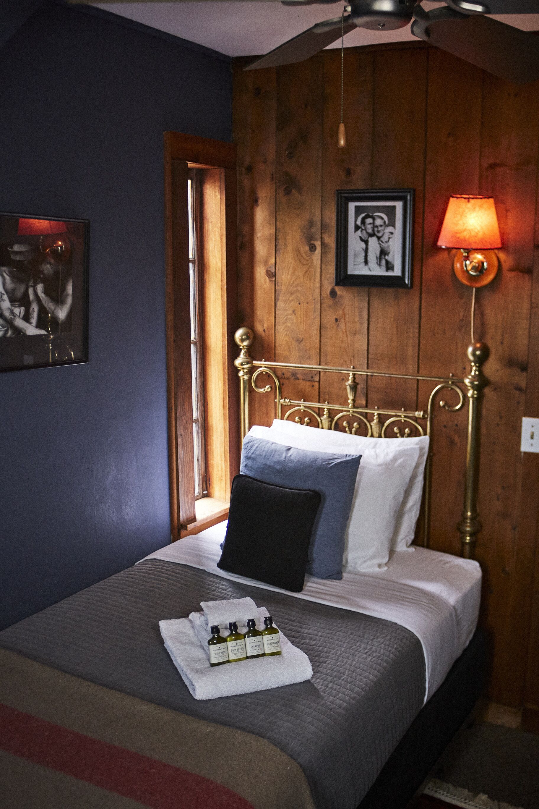 A bed with a metal headboard, a bedside lamp, and a framed photo on the wall.