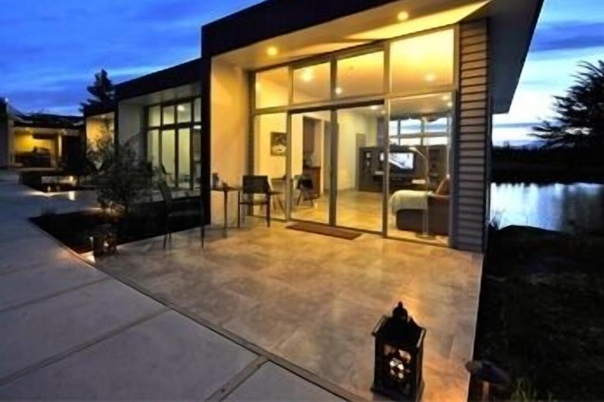 A modern house with a glass facade, a patio area, and a pool.