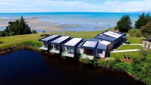 Une propriété moderne située au bord de l’eau, comprenant plusieurs bâtiments, un quai et offrant une vue sur la mer.