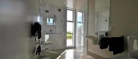 A modern bathroom with a toilet, sink, and mirror. There is a window providing natural light.