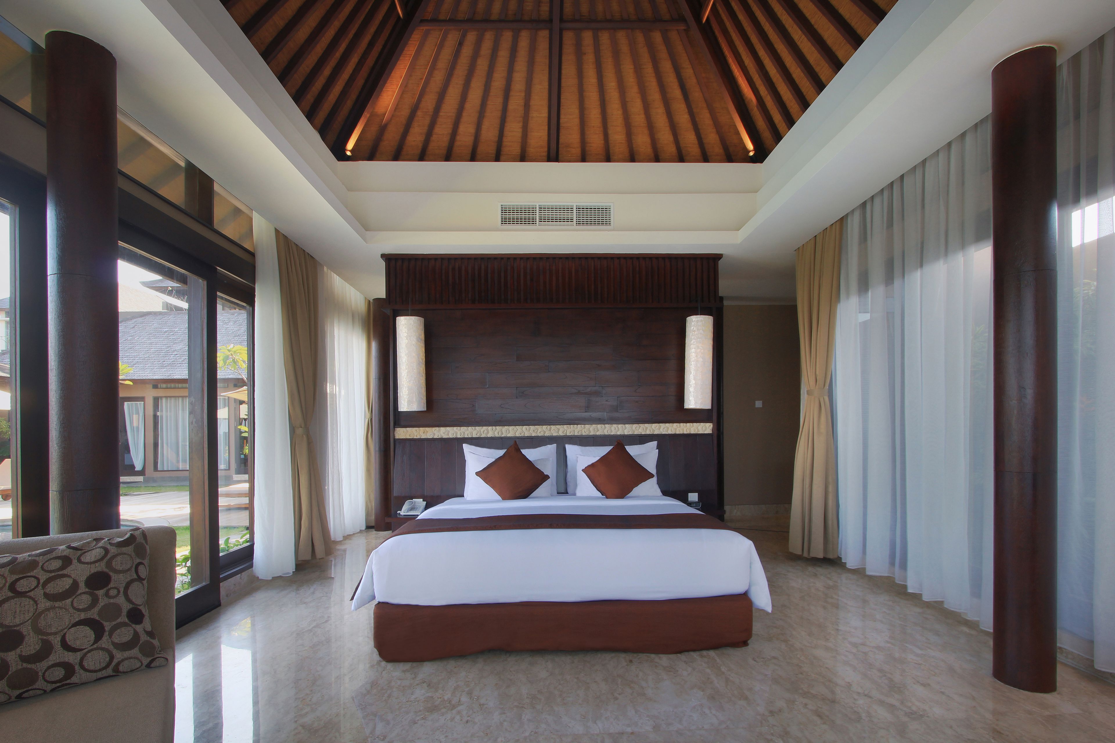 Un dormitorio amplio con una cama grande, techo de madera y ventanas espaciosas.