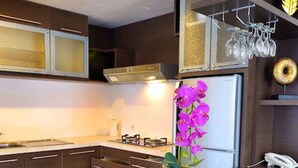 Cozinha moderna com armários de madeira escura, uma ilha central com banquetas, uma geladeira e um vaso de orquídeas decorativas.