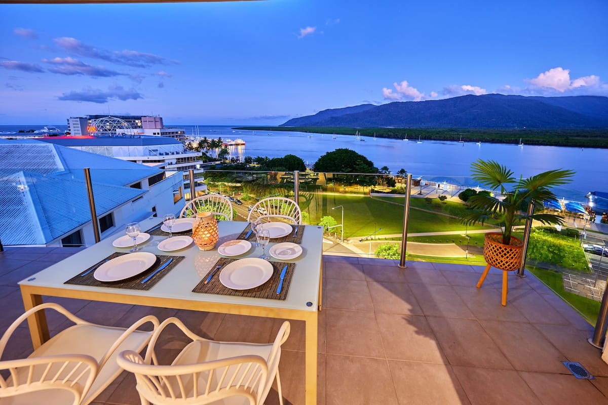 A dining table set for four with a view of a lake and mountains in the background.