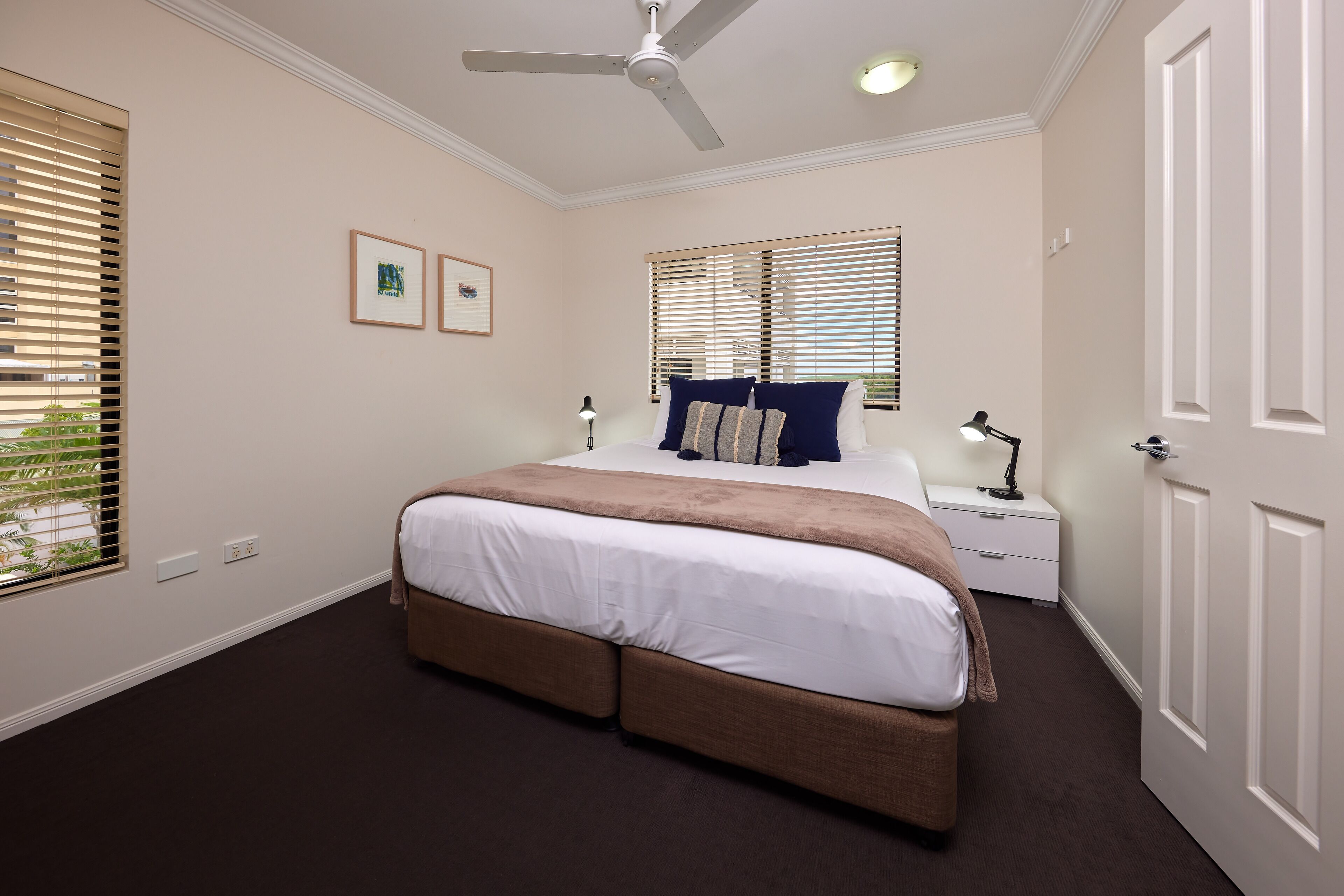 Ein Schlafzimmer mit einem großen Bett, einem Deckenventilator, einem Nachttisch und einer Tür.