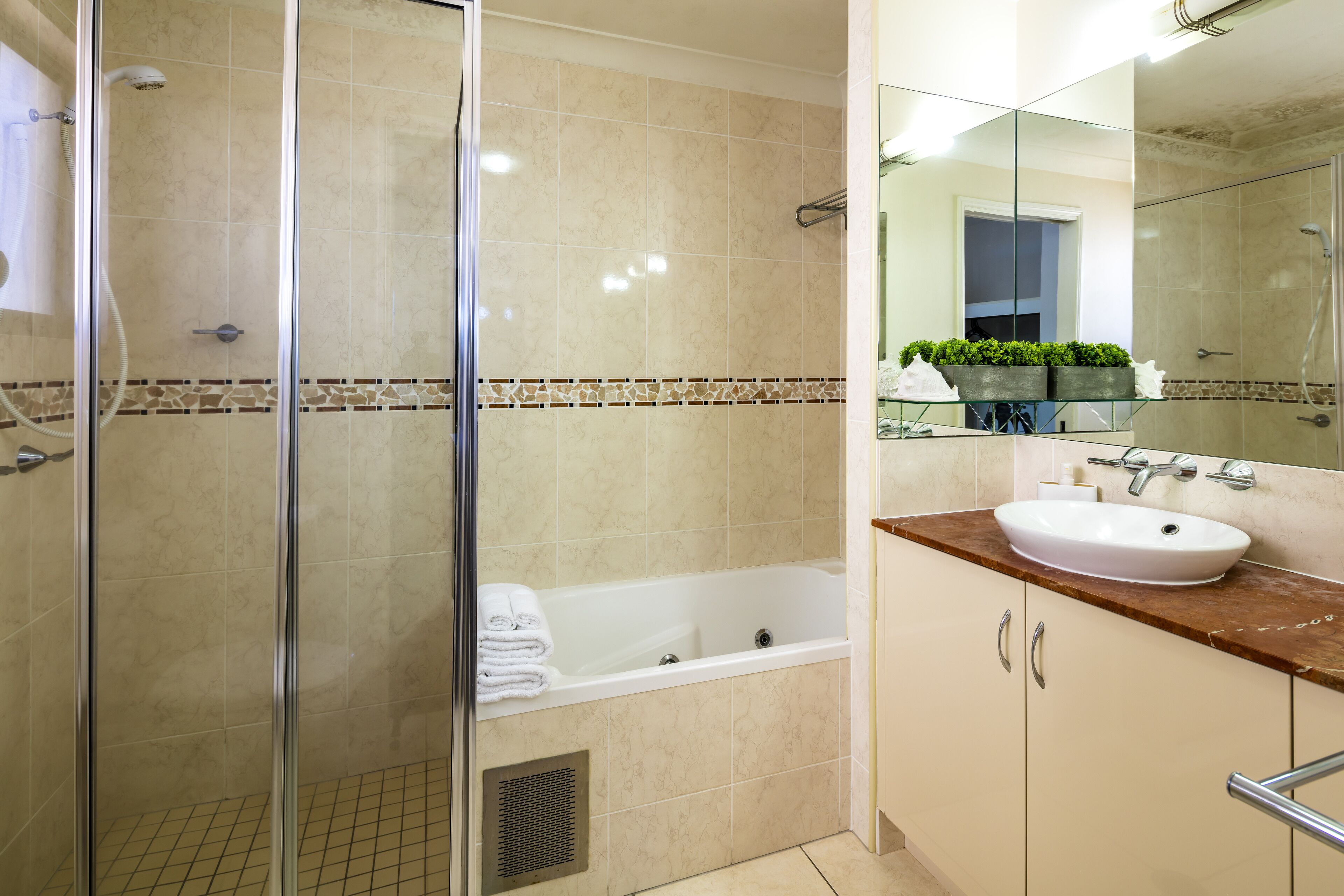 Un baño moderno con ducha de vidrio, una bañera blanca y un tocador con lavamanos y espejo.