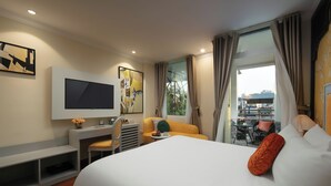 A hotel room with a bed, a desk, a chair, a TV, and a window with curtains.