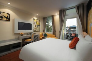 A hotel room with a bed, a desk, a chair, a TV, and a window with curtains.