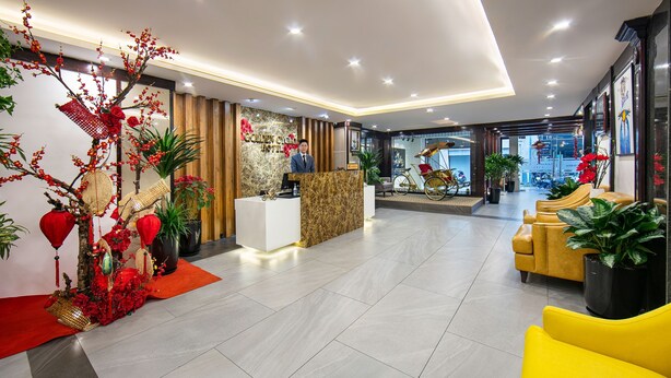 A hotel reception area with a marble counter, red decorative elements, and yellow seating.