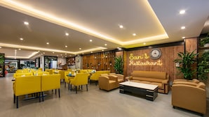 A modern restaurant interior with yellow and brown seating, a neon sign, and a wooden accent wall.