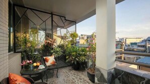 A balcony with a table, chairs, and potted plants.