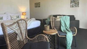 A hotel room with a bed, two wicker chairs, a small table, and a sofa. - Heritage Resort Shark Bay (Denham)