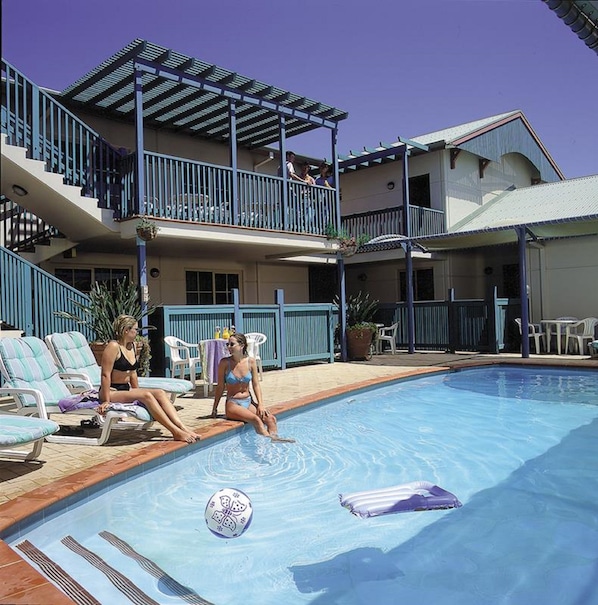 Una piscina al aire libre, sillones reclinables de piscina