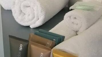 Un baño con toallas blancas ordenadas, una bandeja con tres productos de 'Kudos Spa' y un espejo.