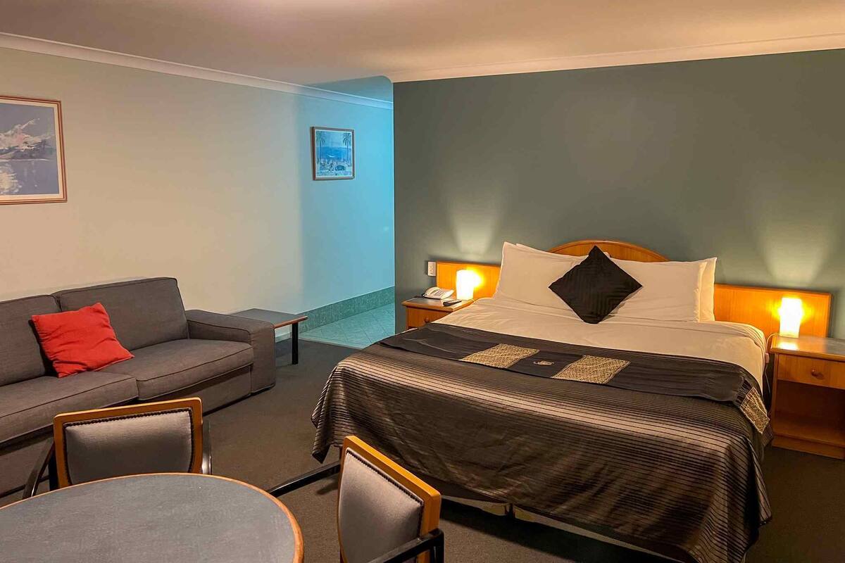 A hotel room with a bed, a sofa, a small table, and two chairs.