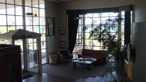 A spacious lobby with large windows, a reception desk, a seating area with a table, and a potted plant. - Heritage Resort Shark Bay (Denham)