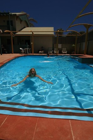 Una piscina al aire libre, sillones reclinables de piscina