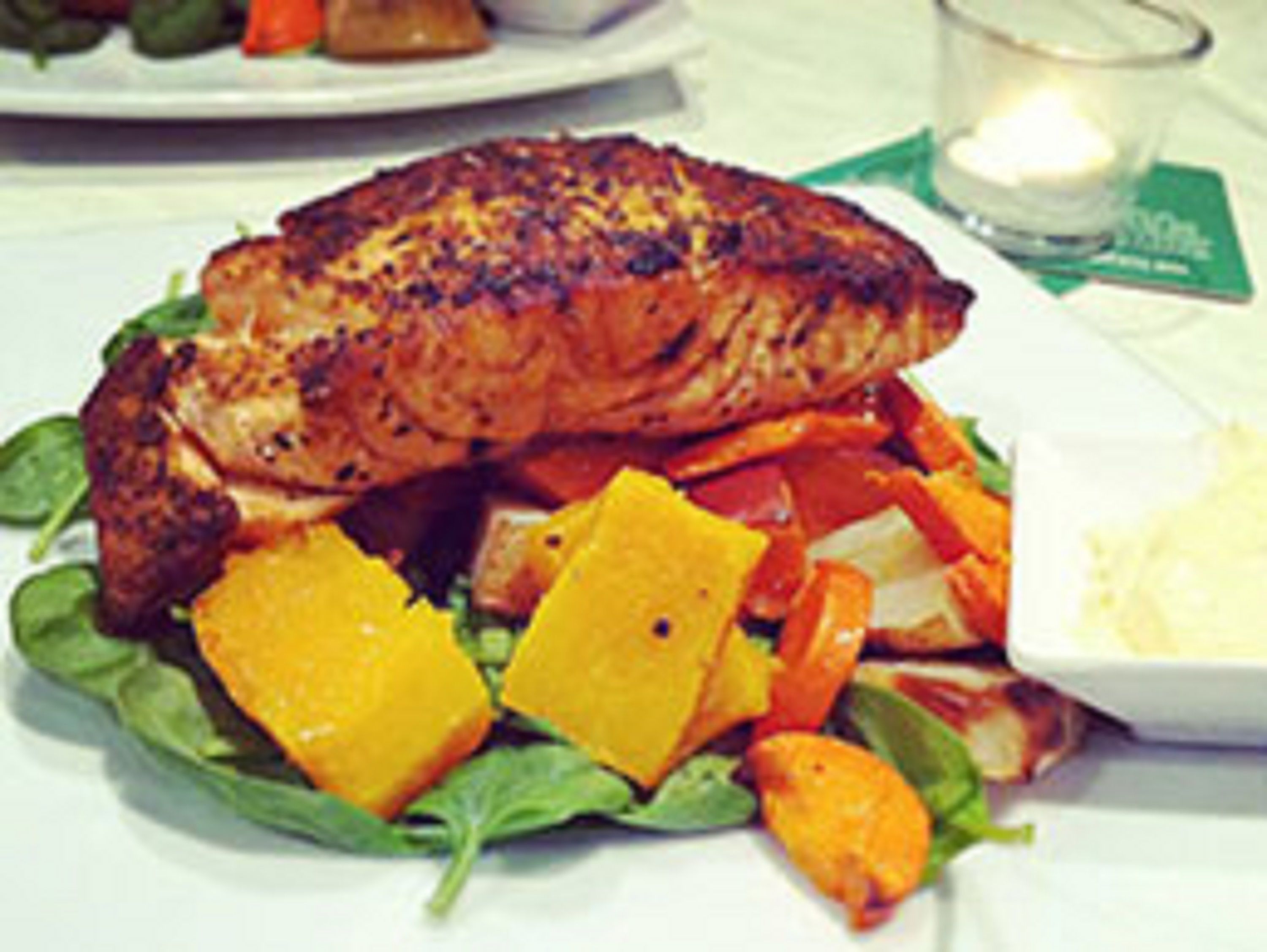A plate with grilled salmon, orange slices, and greens.