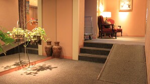 A hotel lobby with a staircase, a red chair, a lamp, and potted plants. - Sapporo Classe Hotel (Sapporo)