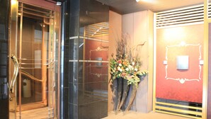 A hotel entrance with a glass door, a staircase, and a decorative floral arrangement. - Sapporo Classe Hotel (Sapporo)