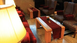 A cozy lobby with red upholstered seating, a wooden coffee table, and a large floor lamp. - Sapporo Classe Hotel (Sapporo)