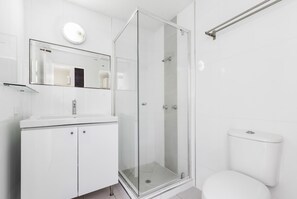 A modern bathroom with a glass-enclosed shower, a white sink, and a toilet. - Mylos Holiday Apartments (Maroochydore)