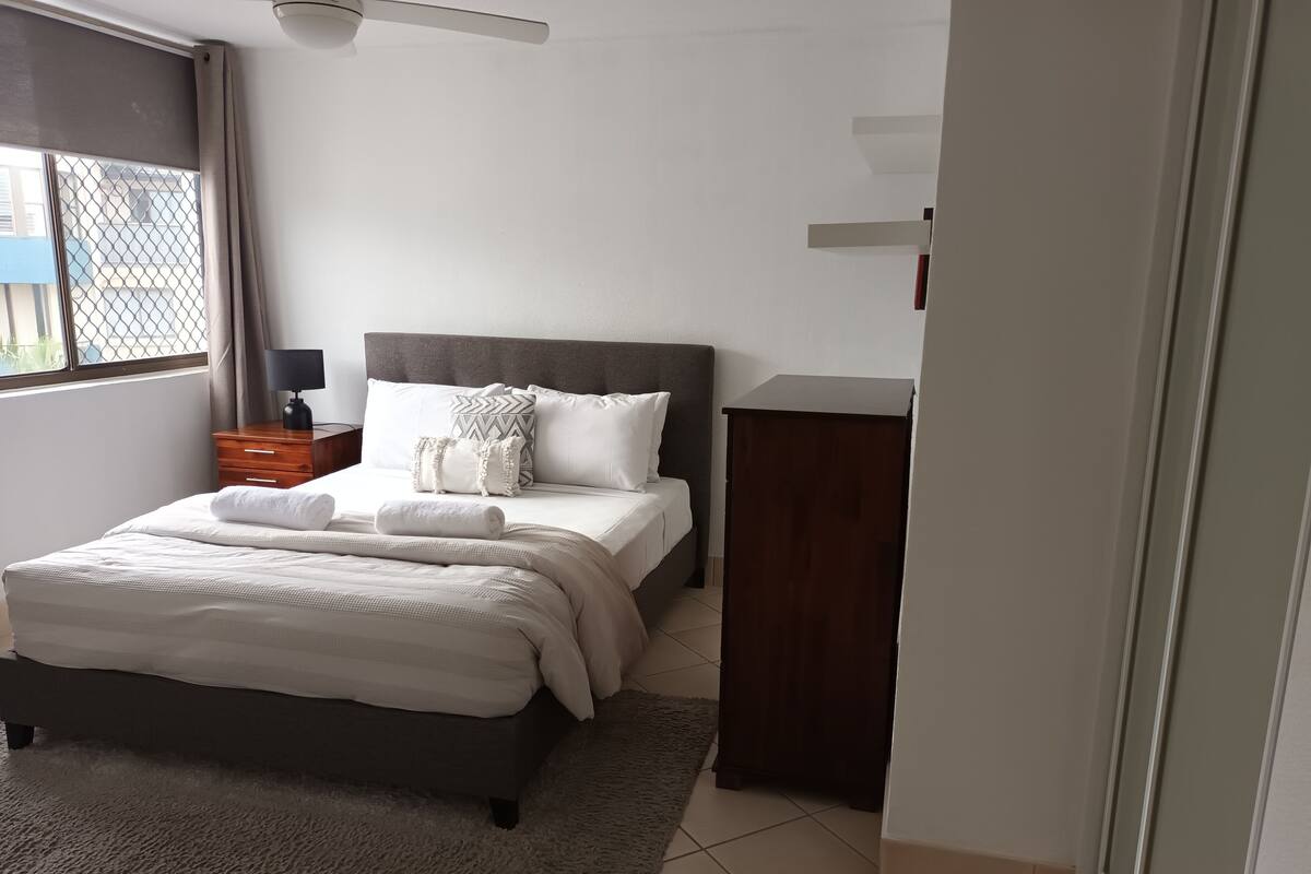 A neatly arranged bedroom with a bed, bedside table, and a dresser.