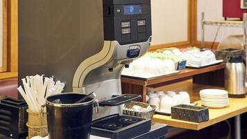 Una cafetera con pantalla digital, un cesto de pajitas, un termo y una pila de platos sobre una encimera.