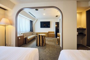 Habitación de hotel con una cama grande, un sofá, una mesita, un televisor y un baño.