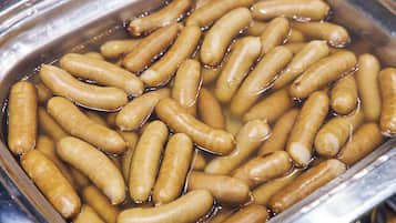 A container filled with sausages submerged in a liquid.